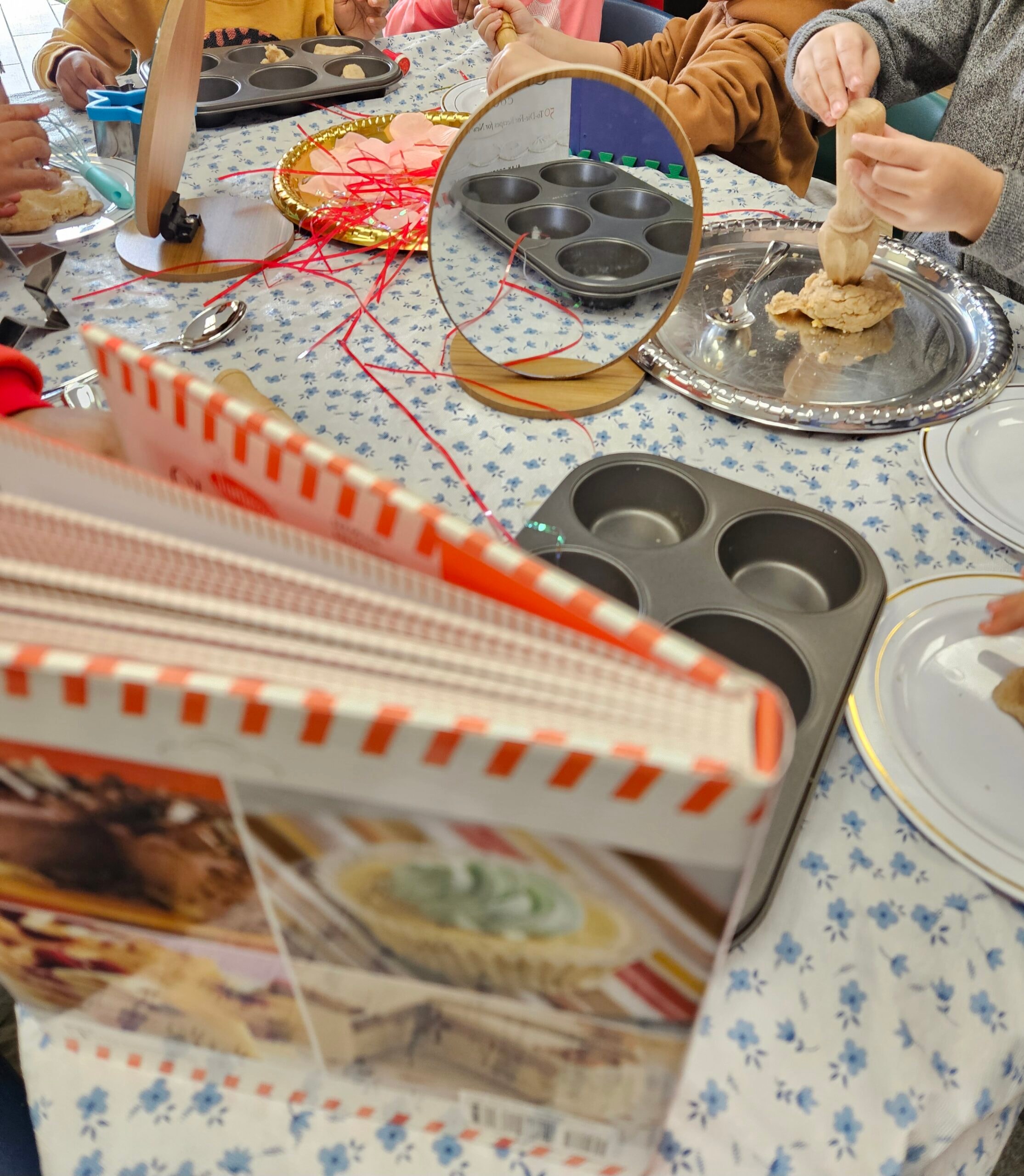 Children working with playdough and baking supplies at a decorated table