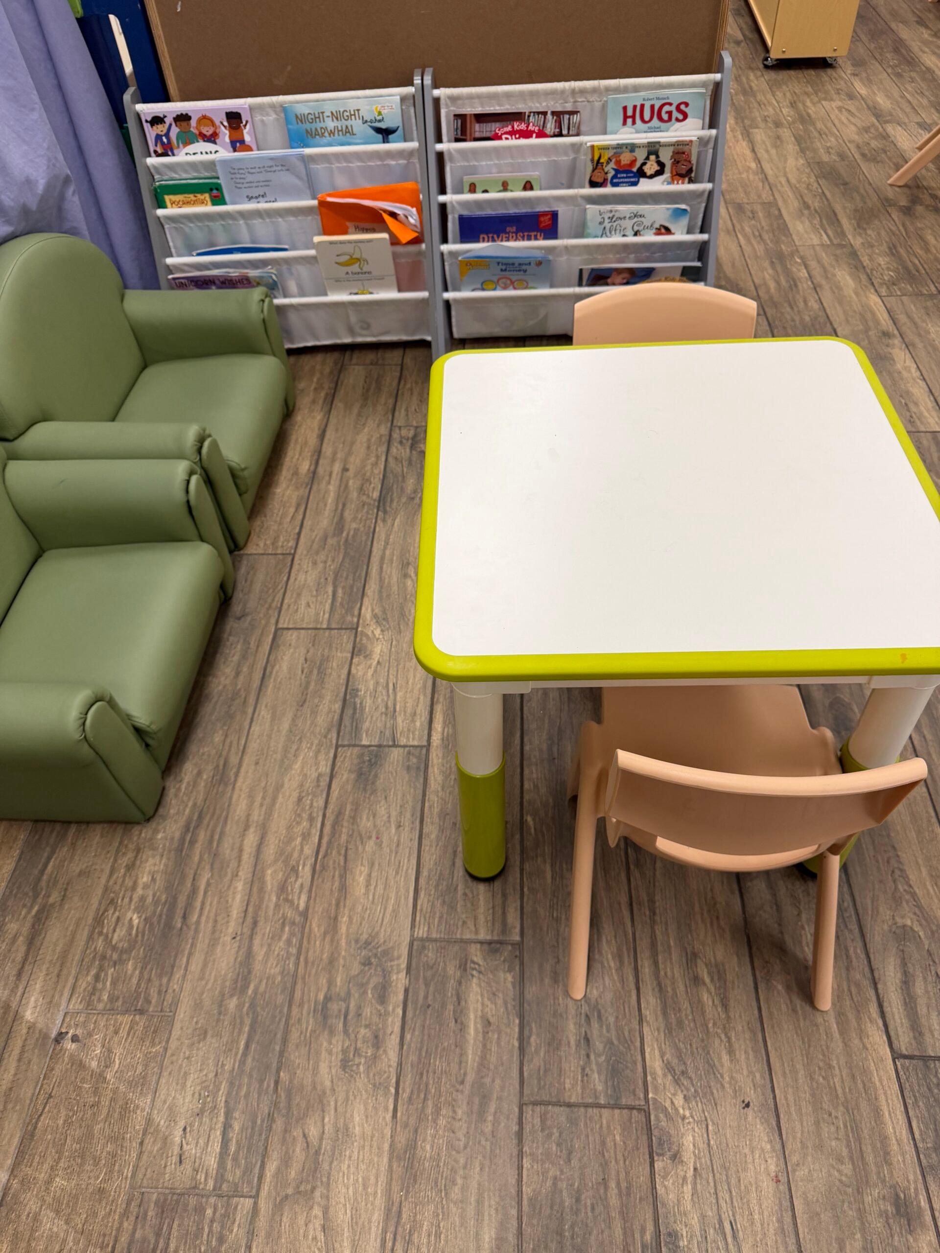 Preschool reading nook with green sofa, book displays, and activity table