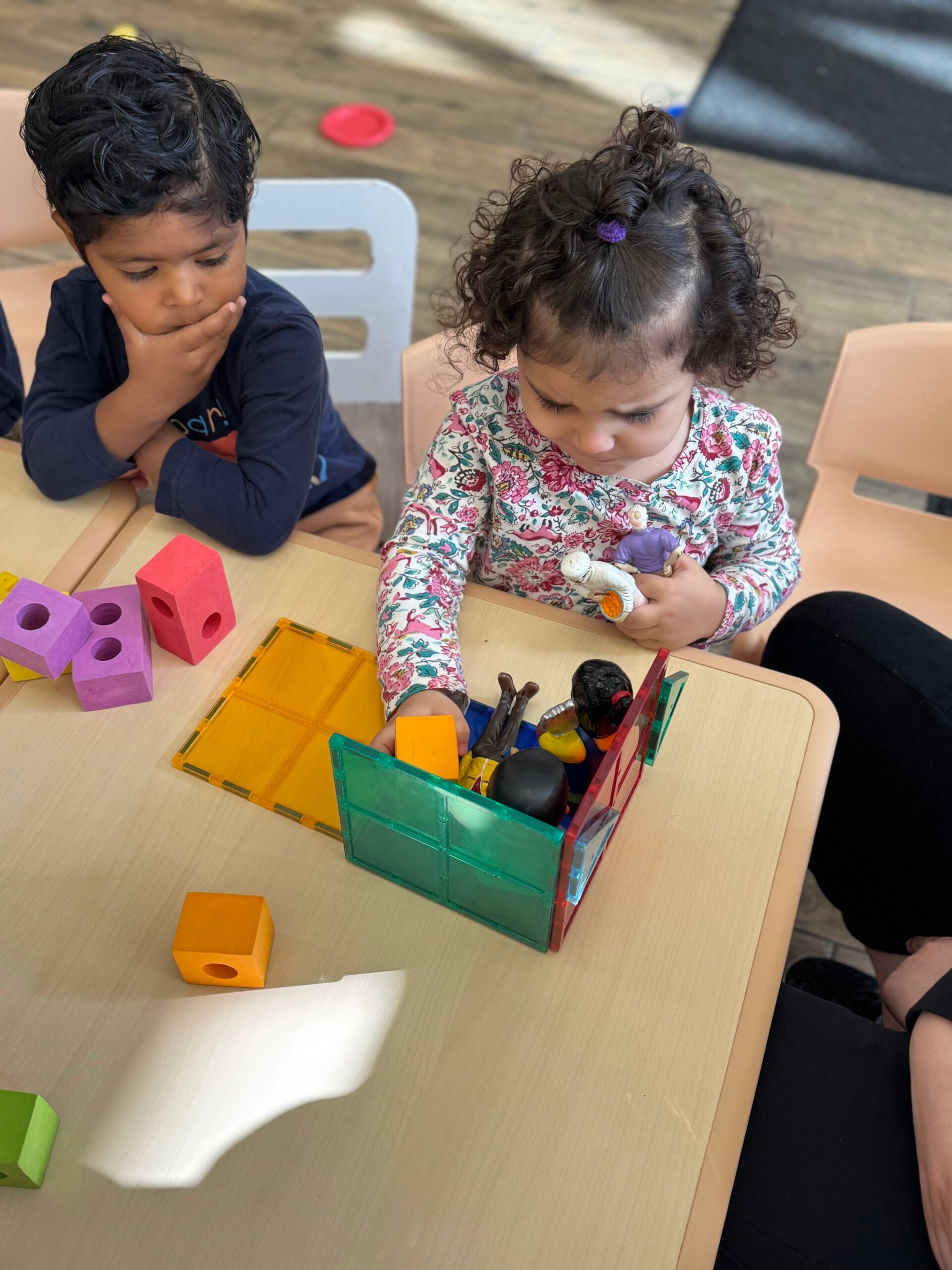 Toddlers playing with colourful building blocks and magnetic tiles