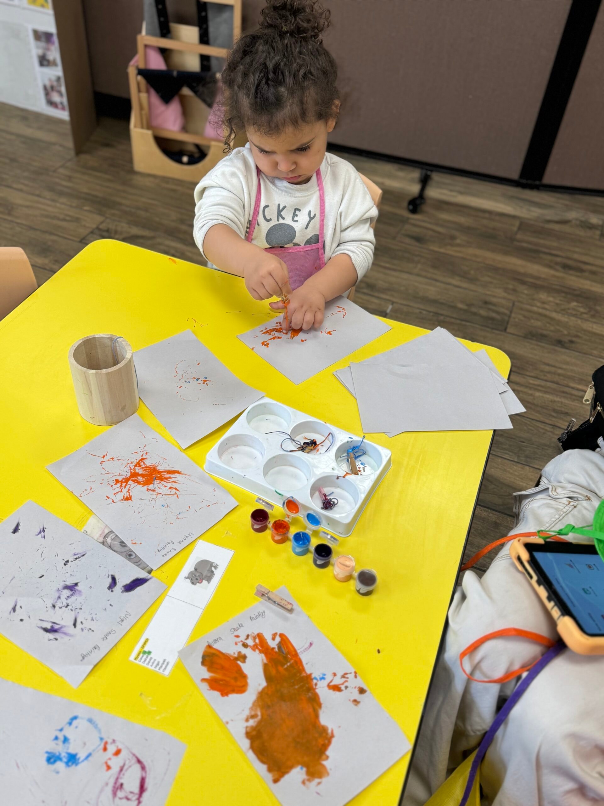 Toddler doing a painting art activity at a yellow table