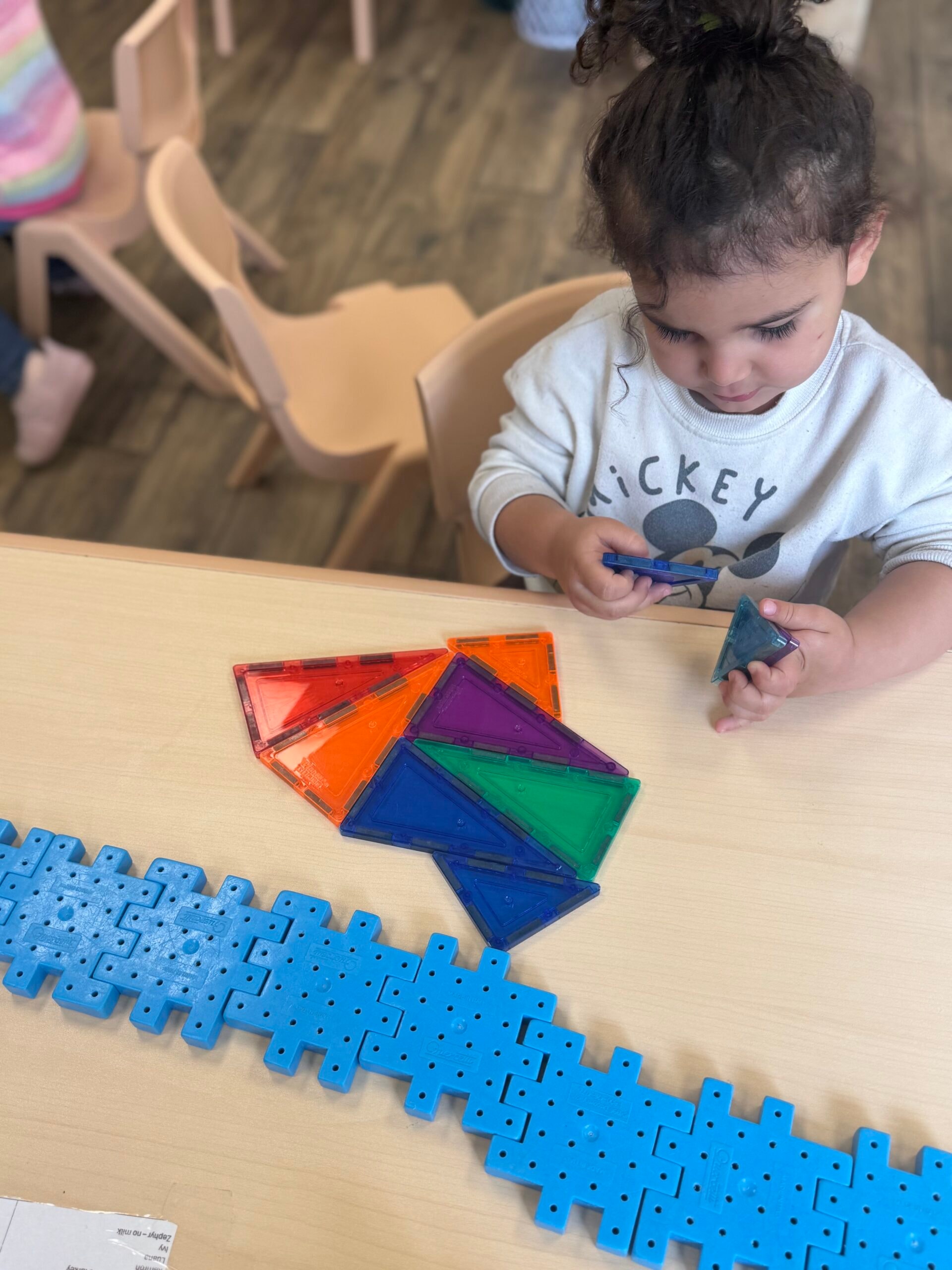 Toddler arranging colourful magnetic triangle tiles