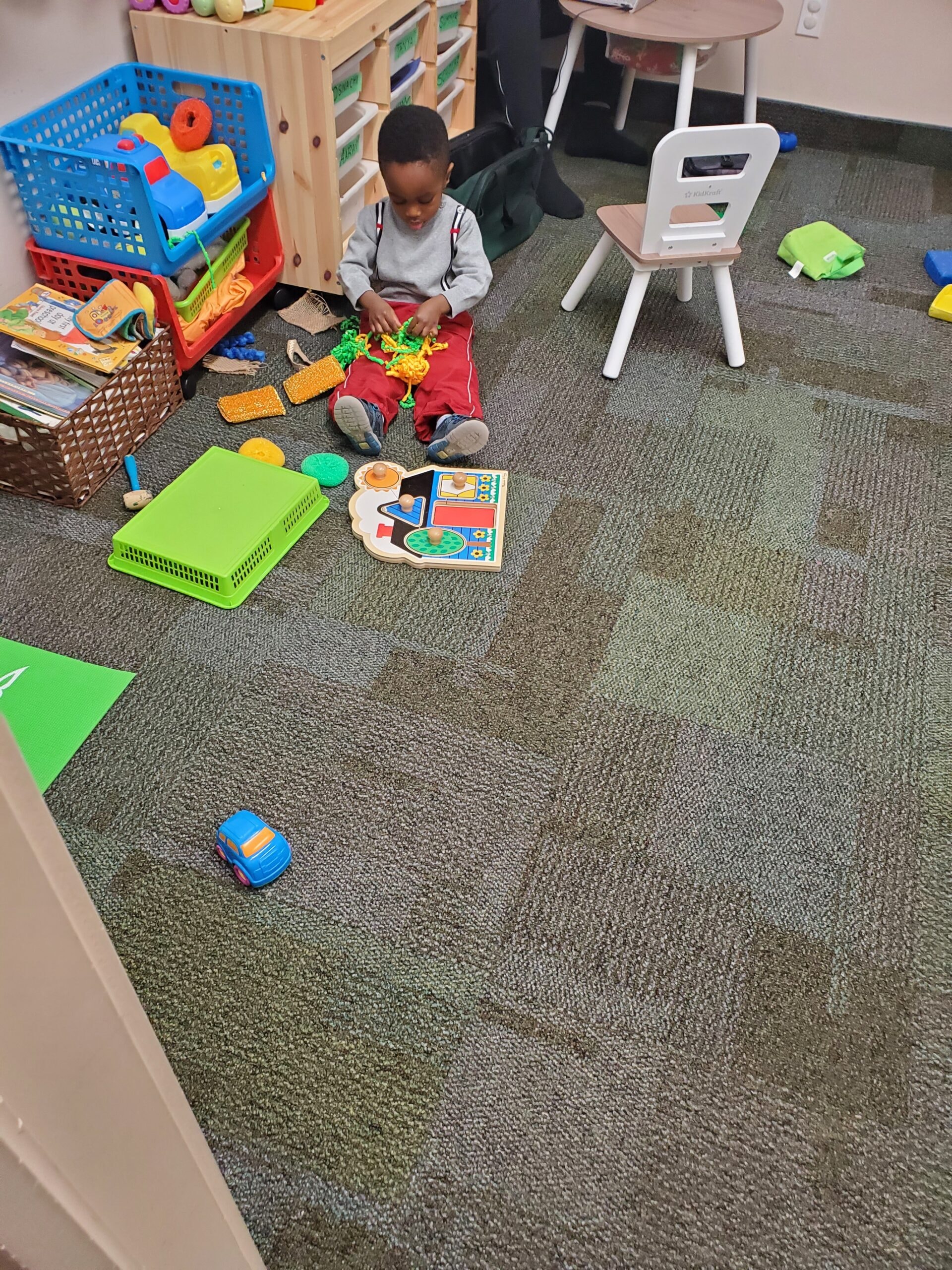 Toddler playing independently with toys on the classroom floor